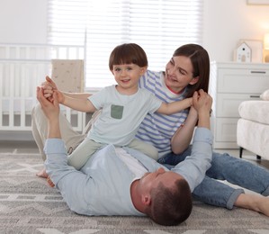 Photo of Cute little boy and his parents having fun at home. Lovely family