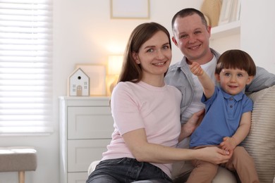 Photo of Cute little boy and his parents on sofa at home, space for text. Lovely family-
