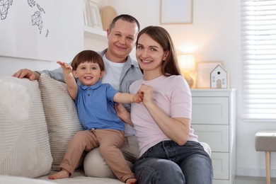 Photo of Cute little boy and his parents on sofa at home. Lovely family