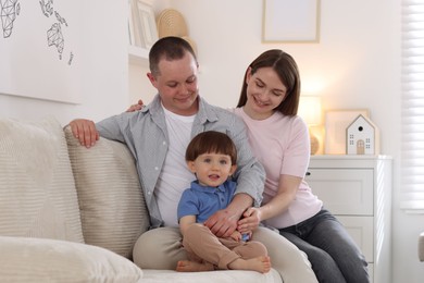 Photo of Cute little boy and his parents on sofa at home. Lovely family