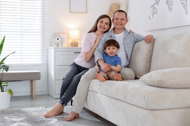 Photo of Cute little boy and his parents on sofa at home, space for text. Lovely family