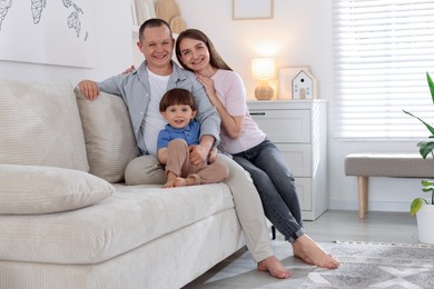 Photo of Cute little boy and his parents on sofa at home, space for text. Lovely family