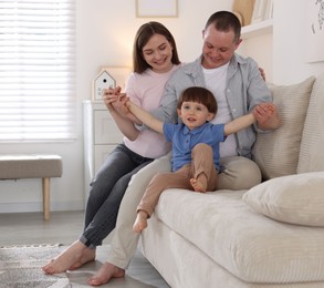 Photo of Cute little boy and his parents on sofa at home. Lovely family