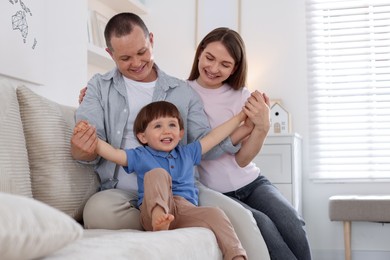 Photo of Cute little boy and his parents on sofa at home. Lovely family