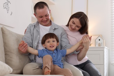 Photo of Cute little boy and his parents on sofa at home. Lovely family