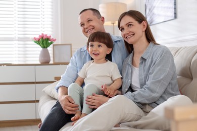 Photo of Cute little boy and his parents on sofa at home. Lovely family