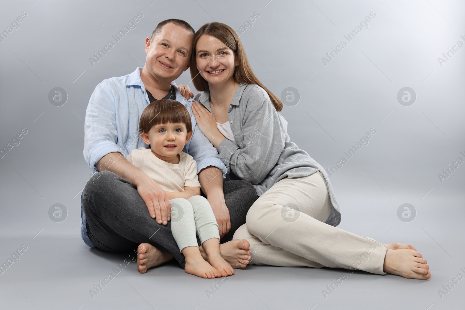Happy parents and their baby boy on light grey background. Lovely family Photo of Happy parents and their baby boy on light grey background. Lovely family