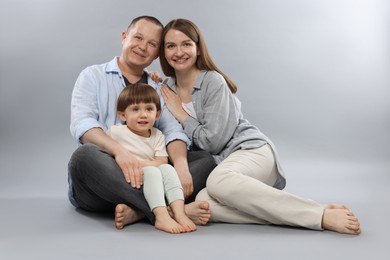 Photo of Happy parents and their baby boy on light grey background. Lovely family
