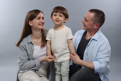 Photo of Happy parents and their baby boy on light grey background. Lovely family