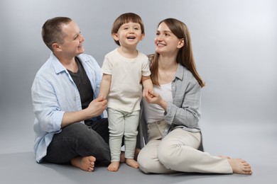 Photo of Happy parents and their baby boy on light grey background. Lovely family