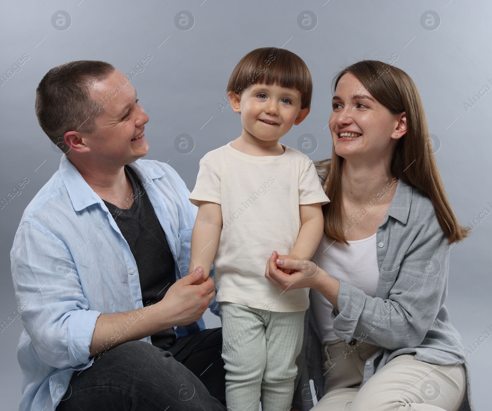 Happy parents and their baby boy on light grey background. Lovely family Photo of Happy parents and their baby boy on light grey background. Lovely family