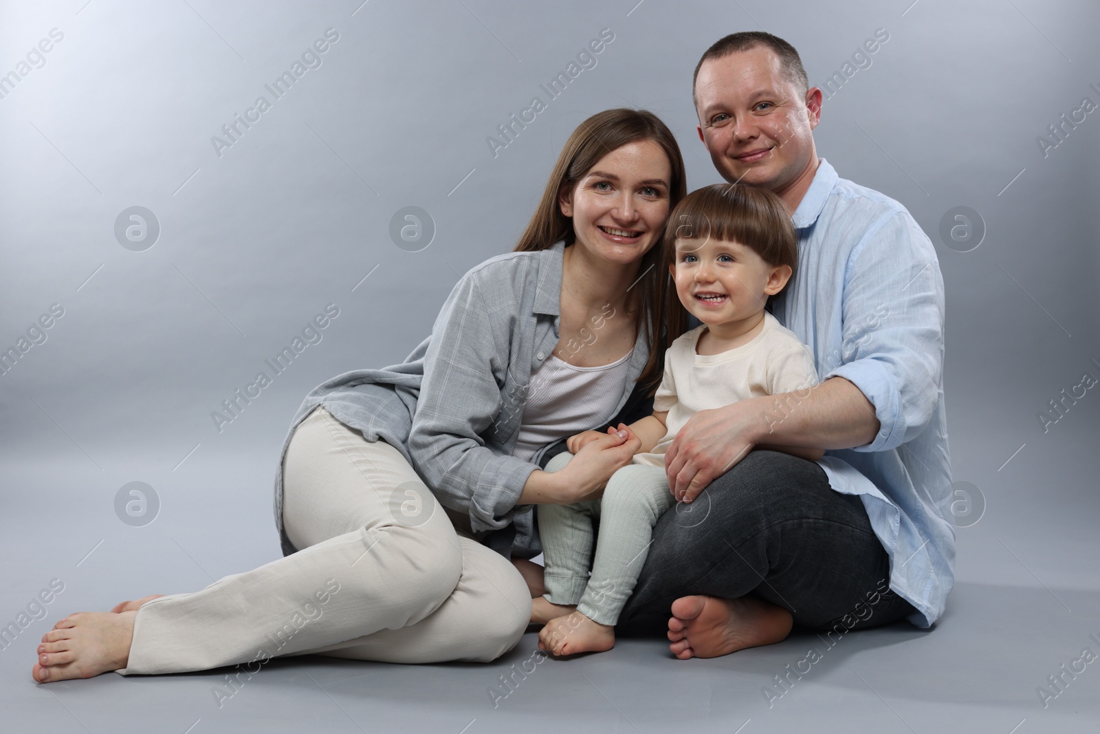 Happy parents and their baby boy on light grey background. Lovely family Photo of Happy parents and their baby boy on light grey background. Lovely family