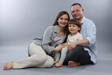 Photo of Happy parents and their baby boy on light grey background. Lovely family