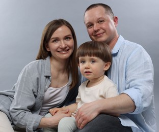 Photo of Happy parents and their baby boy on light grey background. Lovely family