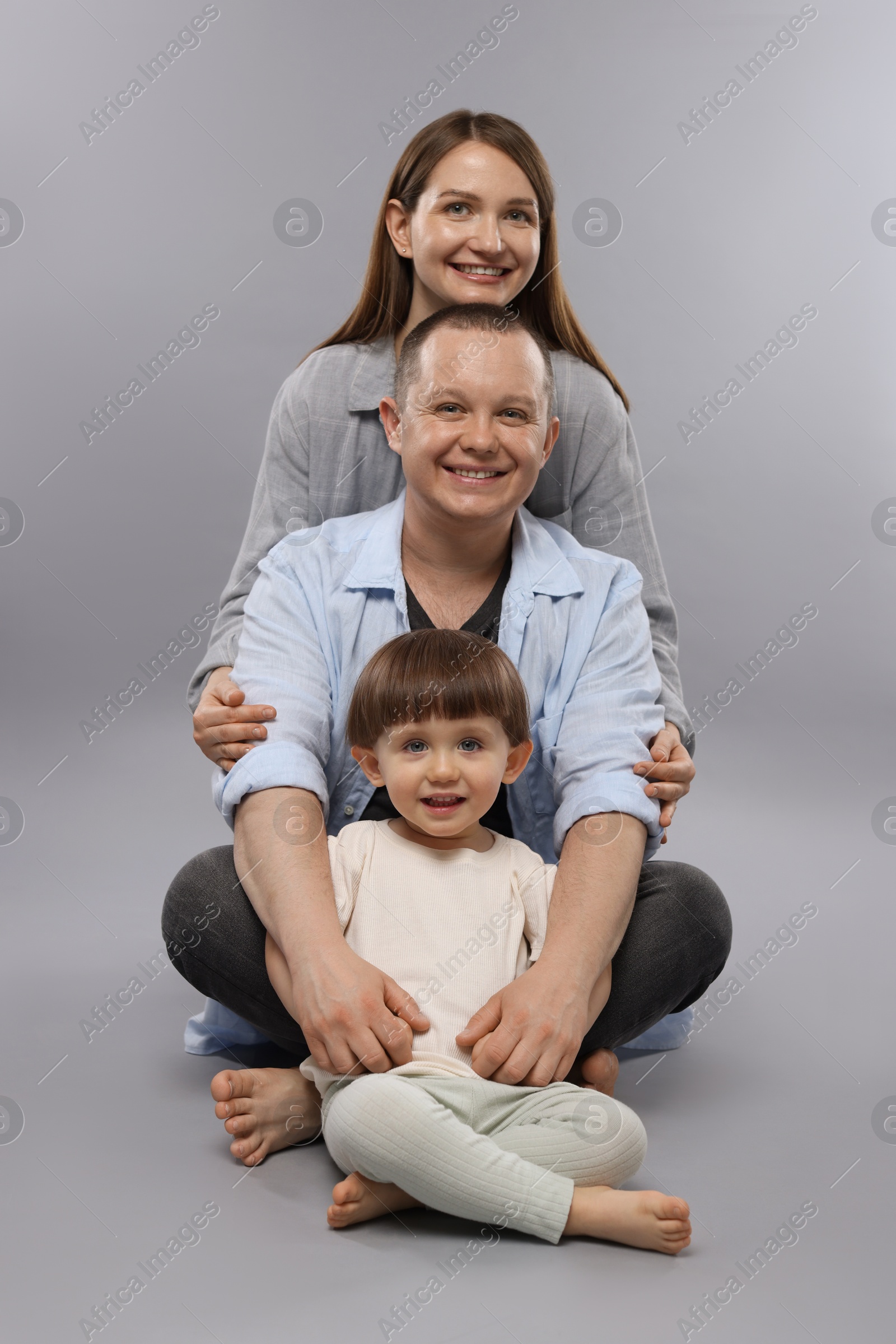 Happy parents and their baby boy on light grey background. Lovely family Photo of Happy parents and their baby boy on light grey background. Lovely family