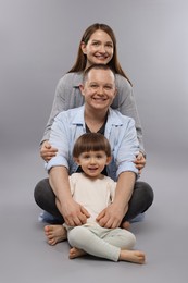 Photo of Happy parents and their baby boy on light grey background. Lovely family