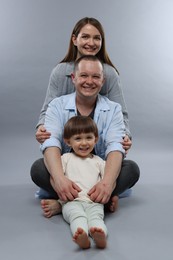 Photo of Happy parents and their baby boy on light grey background. Lovely family