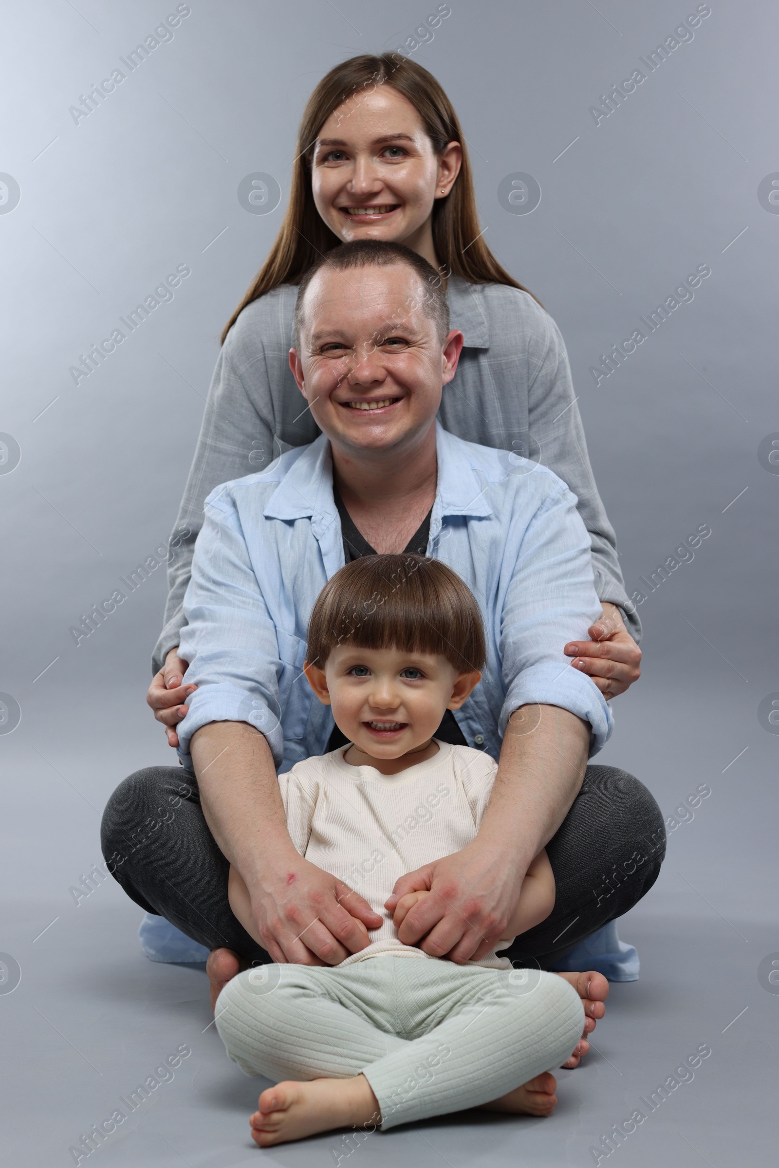 Happy parents and their baby boy on light grey background. Lovely family Photo of Happy parents and their baby boy on light grey background. Lovely family