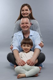 Photo of Happy parents and their baby boy on light grey background. Lovely family