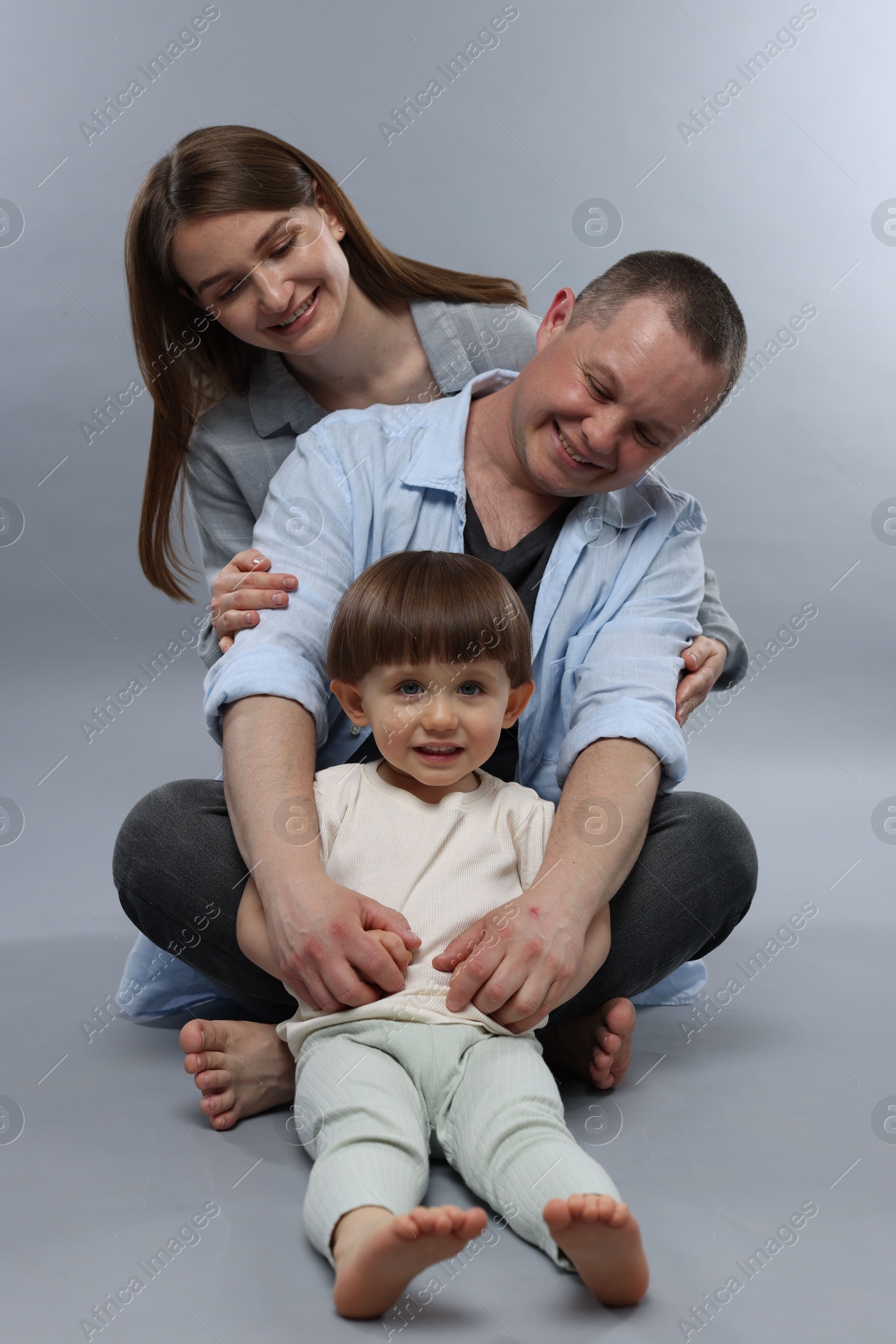 Happy parents and their baby boy on light grey background. Lovely family Photo of Happy parents and their baby boy on light grey background. Lovely family