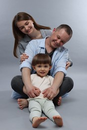 Photo of Happy parents and their baby boy on light grey background. Lovely family