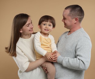 Photo of Happy parents and their baby boy on beige background. Lovely family
