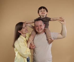 Photo of Happy parents and their baby boy on beige background. Lovely family
