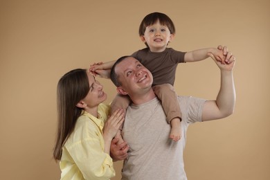 Photo of Happy parents and their baby boy on beige background. Lovely family