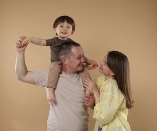 Photo of Happy parents and their baby boy on beige background. Lovely family