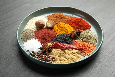 Photo of Different aromatic spices on dark textured table, closeup