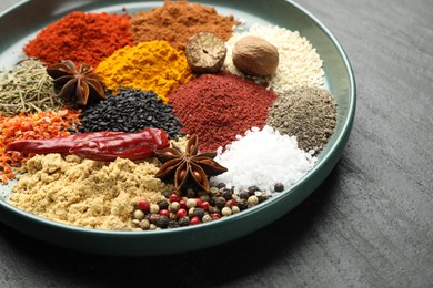Photo of Different aromatic spices on dark textured table, closeup