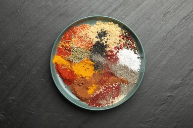 Photo of Different aromatic spices on dark textured table, top view
