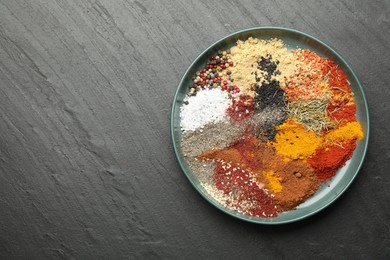 Photo of Different aromatic spices on dark textured table, top view. Space for text