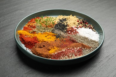 Photo of Different aromatic spices on dark textured table, closeup
