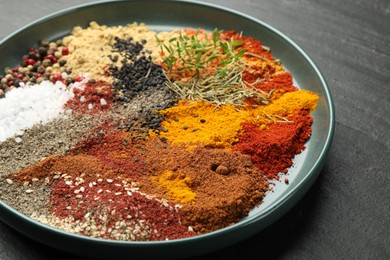 Photo of Different aromatic spices on dark textured table, closeup