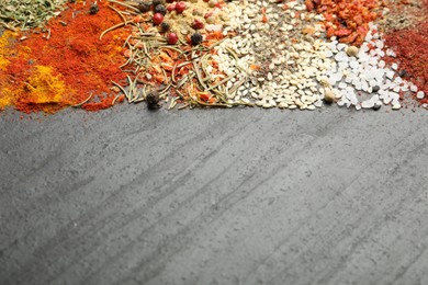 Photo of Different aromatic spices on dark textured table, top view. Space for text