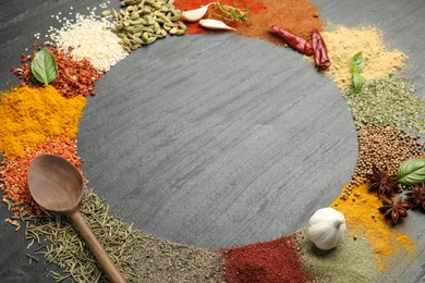 Photo of Different aromatic spices and spoon on dark textured table, t closeup . Space for text