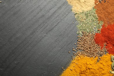 Photo of Different aromatic spices on dark textured table, top view. Space for text