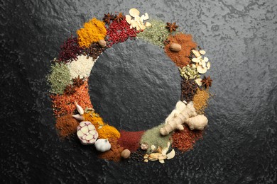 Photo of Different aromatic spices on dark textured table, top view. Space for text