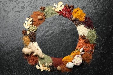 Photo of Different aromatic spices on dark textured table, top view. Space for text