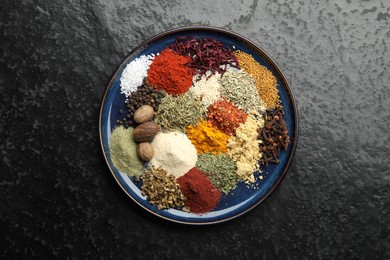 Photo of Different aromatic spices on dark textured table, top view