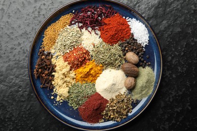 Photo of Different aromatic spices on dark textured table, top view
