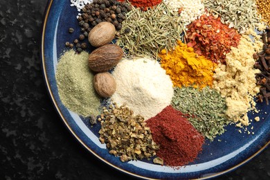 Photo of Different aromatic spices on dark textured table, top view