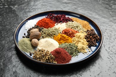 Photo of Different aromatic spices on dark textured table, closeup