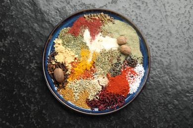 Photo of Different aromatic spices on dark textured table, top view