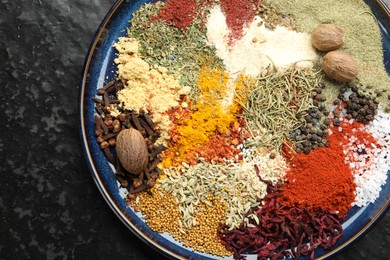 Photo of Different aromatic spices on dark textured table, top view