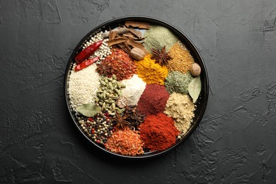 Photo of Different aromatic spices on dark textured table, top view