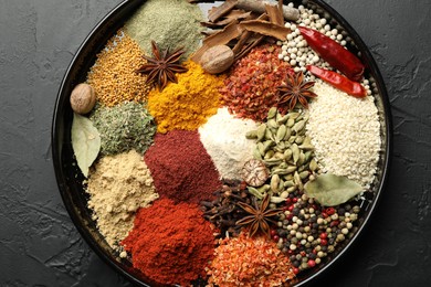 Photo of Different aromatic spices on dark textured table, top view