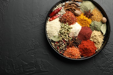 Photo of Different aromatic spices on dark textured table, top view. Space for text