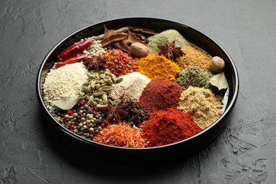 Photo of Different aromatic spices on dark textured table, closeup